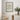 Framed poster with text 'More Espresso Less Depresso' on a wall above a table with decor items.